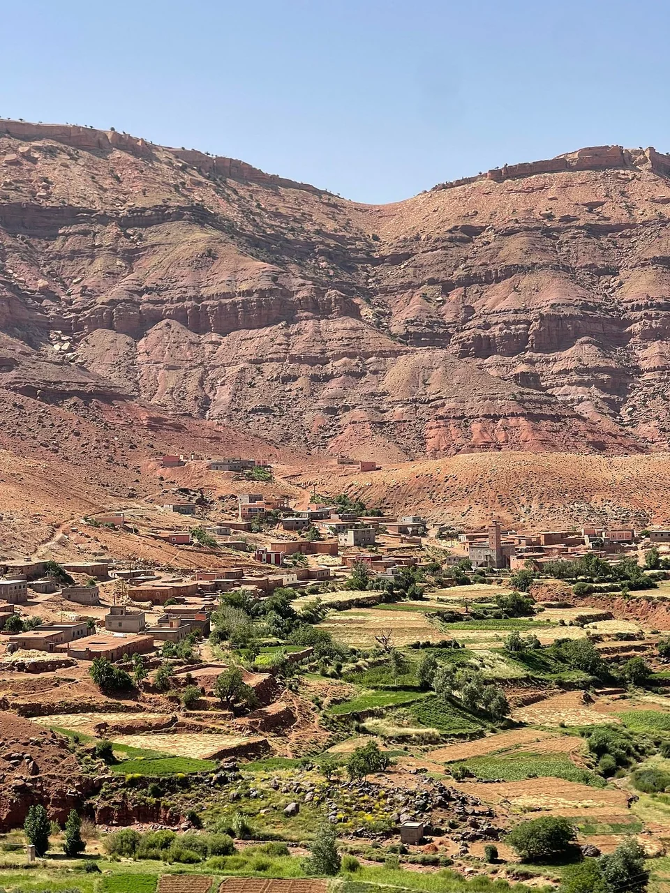 Village and cultivated fields beneath the red cliffs of Dades Valley