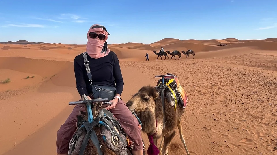 Traveler riding a camel in the Merzouga dunes during a four-day tour to Marrakech