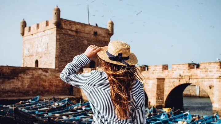 Woman overlooking Essaouira fishing port and historic ramparts