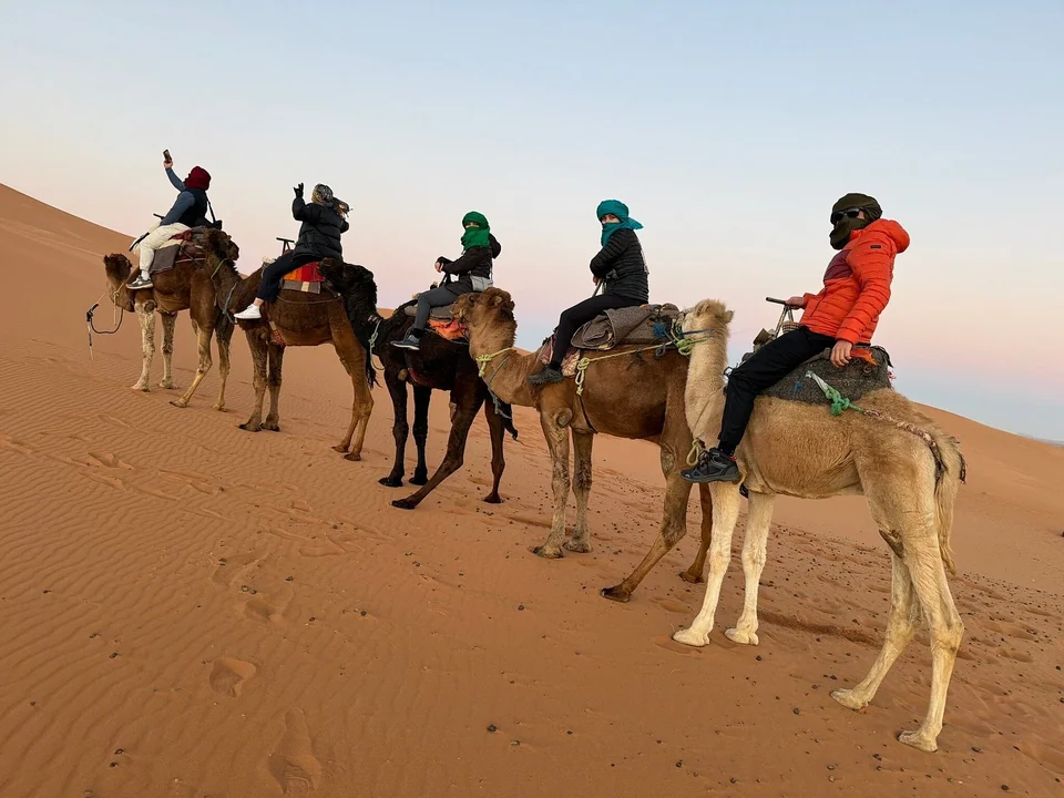 Travelers riding camels during a three-day Merzouga desert tour from Marrakech