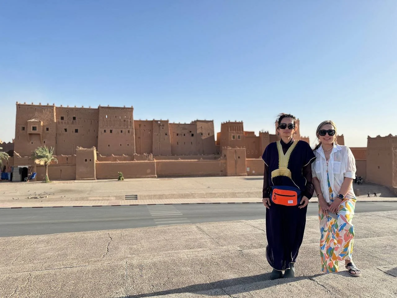 Travelers in front of a traditional kasbah during an Ouarzazate tour